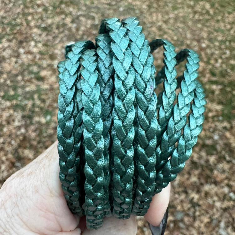 Braided green leather cord held in a hand against a blurred natural background
