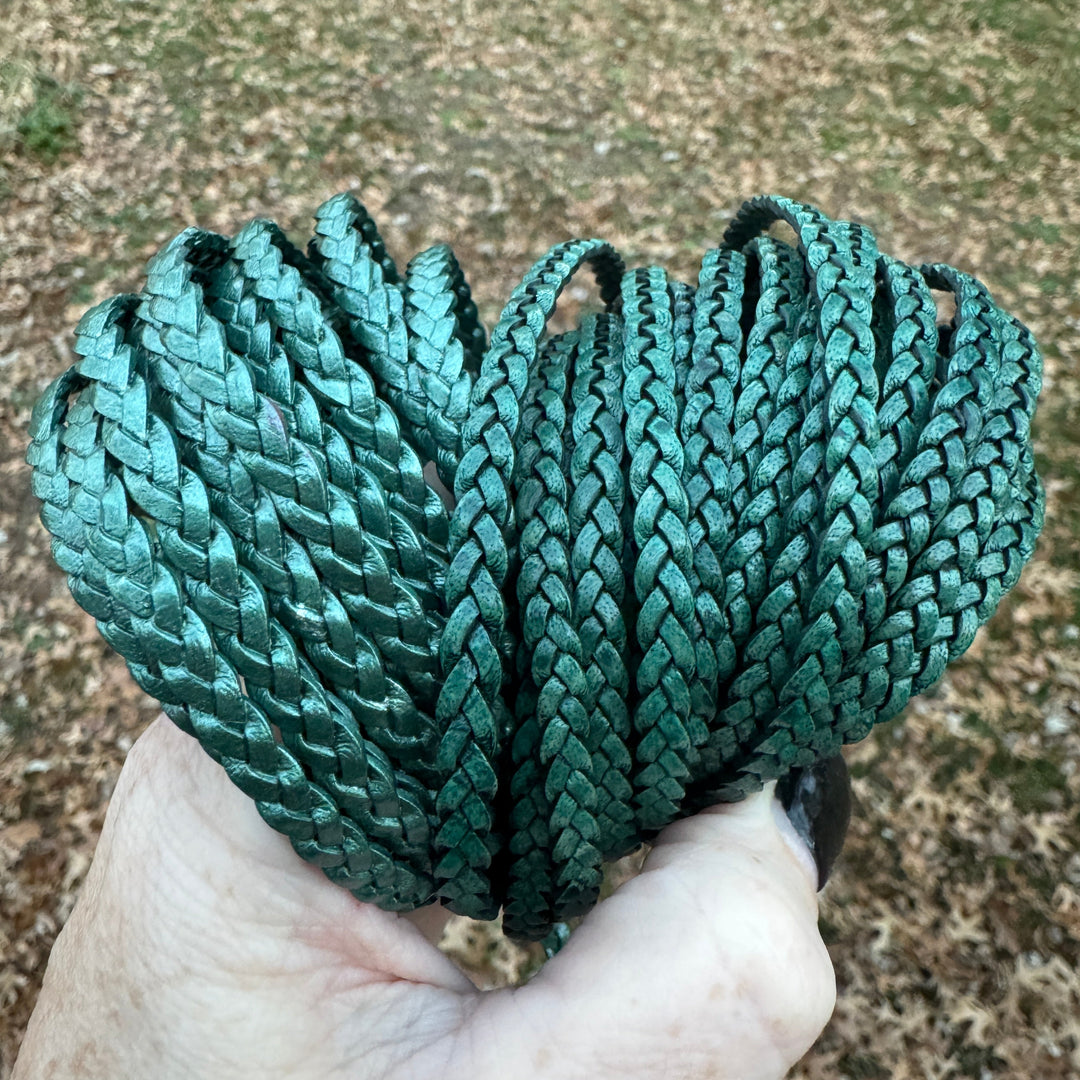 Hand holding a coiled green rope against a textured ground background
